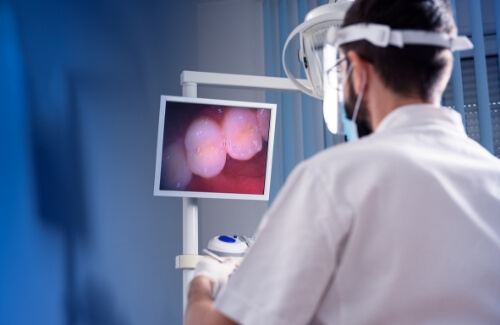 Dentist looking at screen with close up of photos of teeth