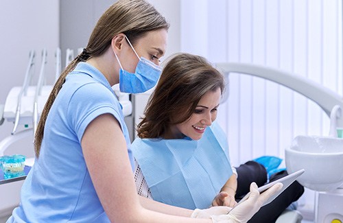 A dentist showing her patient the cost of cosmetic dentistry