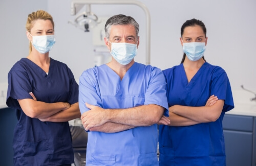Three dental team members wearing personal protective equipment