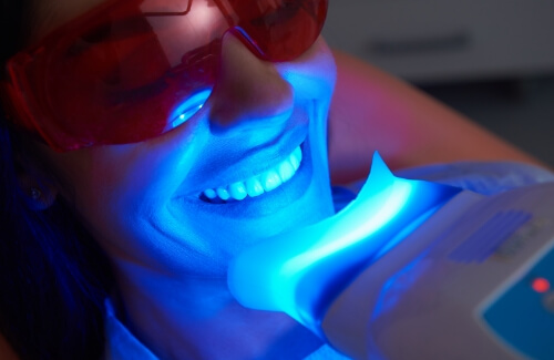 Woman getting professional teeth whitening in dental chair