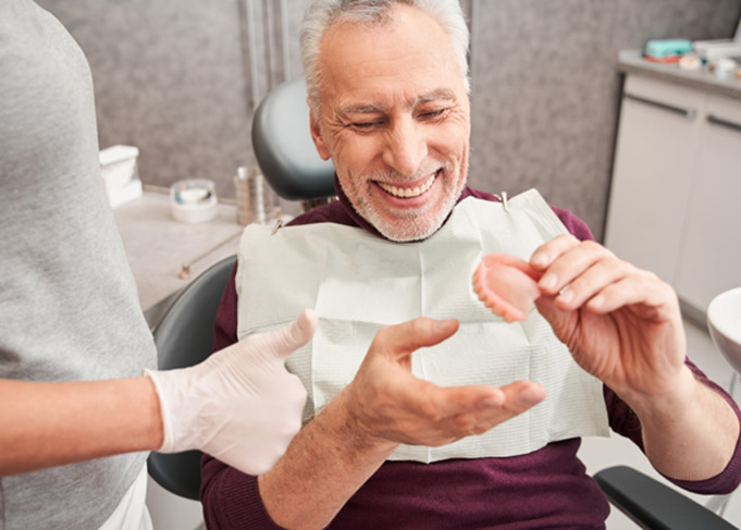 A dentist showing a denture to her older patient