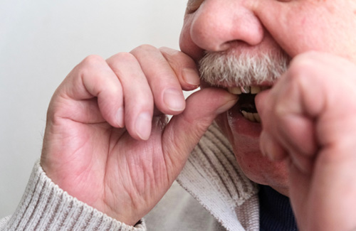 An older man putting dentures in his mouth