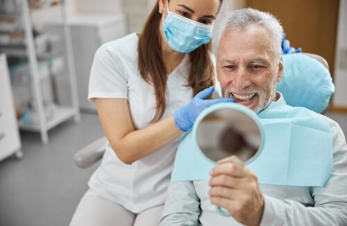 Senior man in dental chair admiring his new smile in a mirror