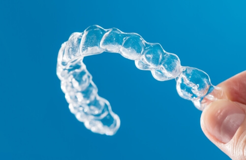 Hand holding an Invisalign clear aligner