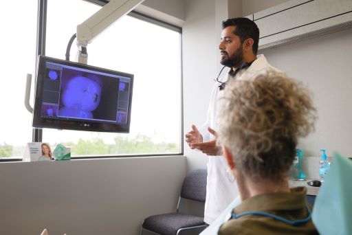 Image of dentist and patient looking at her tooth on screen from client's dropbox
