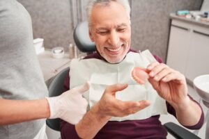 Senior man taking denture at dentist.
