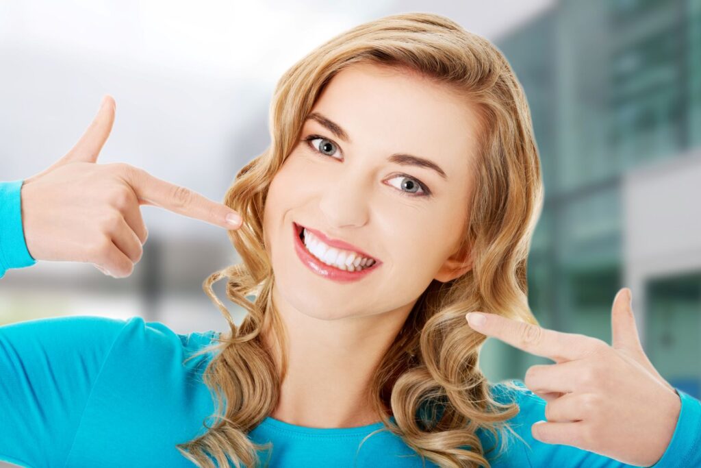 A woman pointing to her improved smile