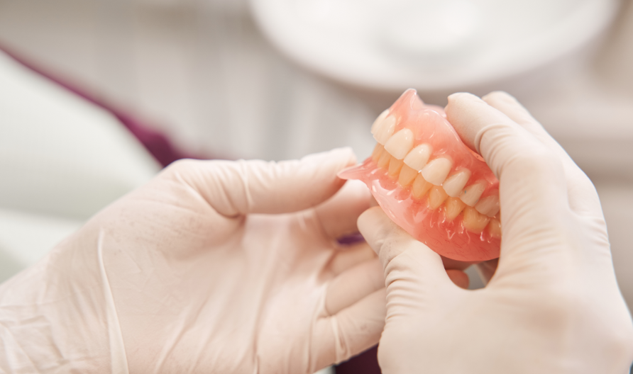 Dentist's gloved hands holding dentures